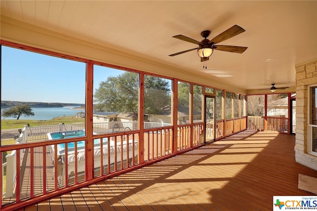 unfurnished sunroom with a water view and ceiling fan