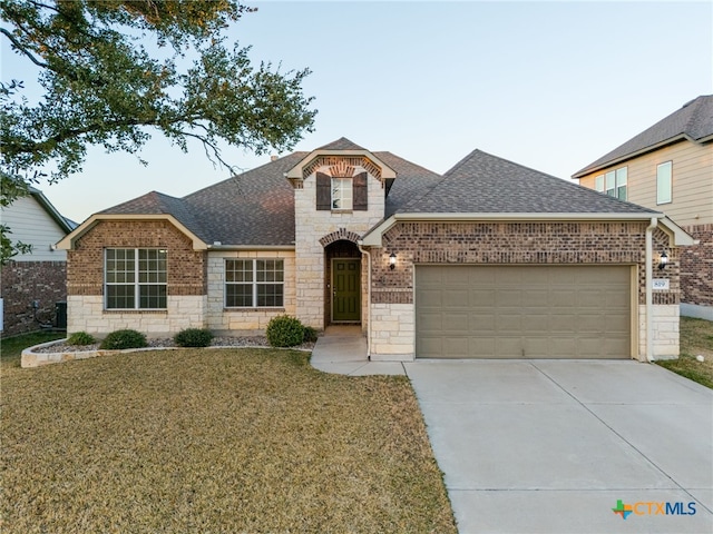 view of front of house featuring a garage, concrete driveway, a shingled roof, and a front yard