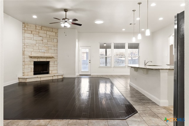 unfurnished living room featuring light wood-type flooring, a healthy amount of sunlight, ceiling fan, and a fireplace