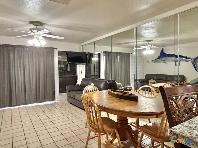 tiled dining space featuring a textured ceiling and ceiling fan