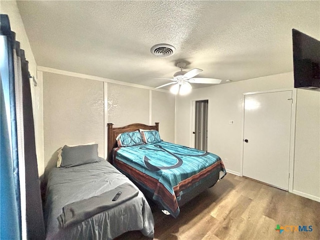 bedroom featuring ceiling fan, hardwood / wood-style flooring, and a textured ceiling