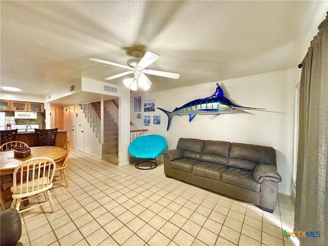 tiled living room featuring a textured ceiling and ceiling fan