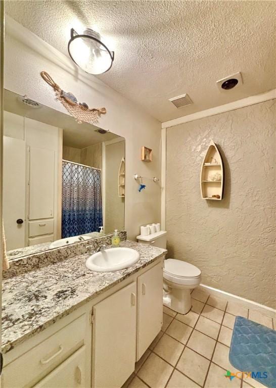 bathroom with tile patterned flooring, vanity, a textured ceiling, and toilet