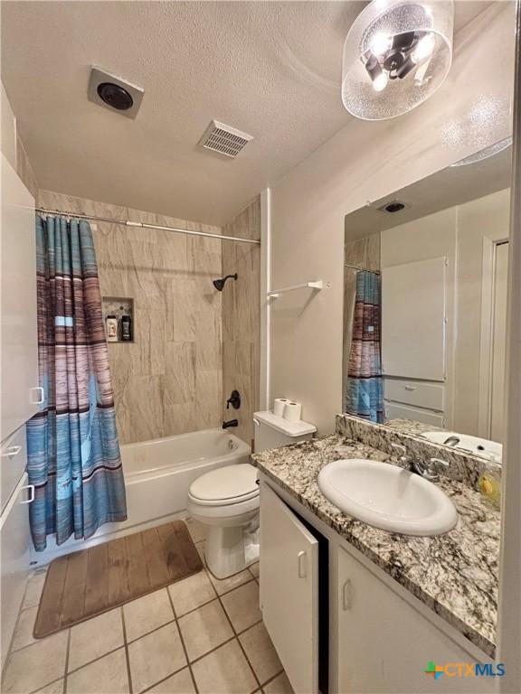 full bathroom with shower / tub combo with curtain, vanity, toilet, tile patterned floors, and a textured ceiling