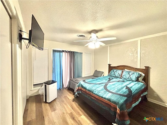 bedroom with hardwood / wood-style floors, a textured ceiling, and ceiling fan