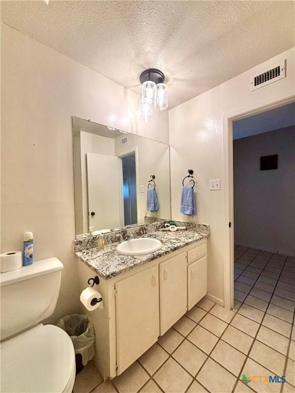 bathroom featuring vanity, tile patterned floors, a textured ceiling, and toilet