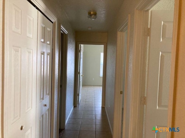 hallway with dark tile patterned floors and a textured ceiling