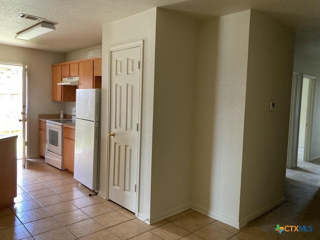 kitchen with light tile patterned floors, white appliances, and a textured ceiling