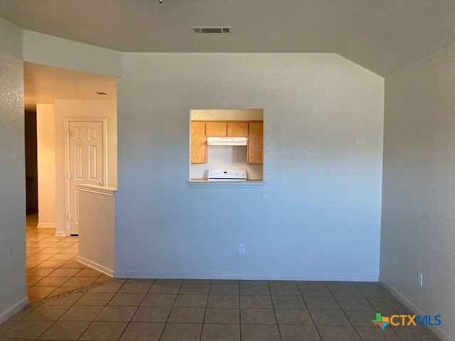 spare room with tile patterned flooring and vaulted ceiling