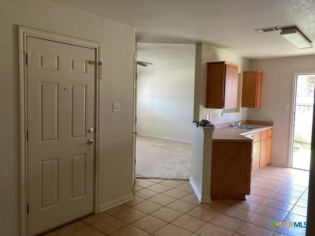 kitchen featuring ceiling fan, sink, light tile patterned floors, and a textured ceiling