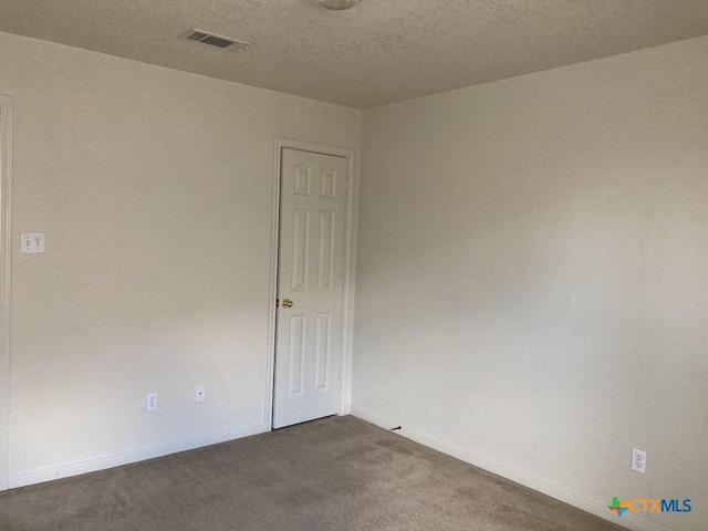 empty room with carpet floors and a textured ceiling