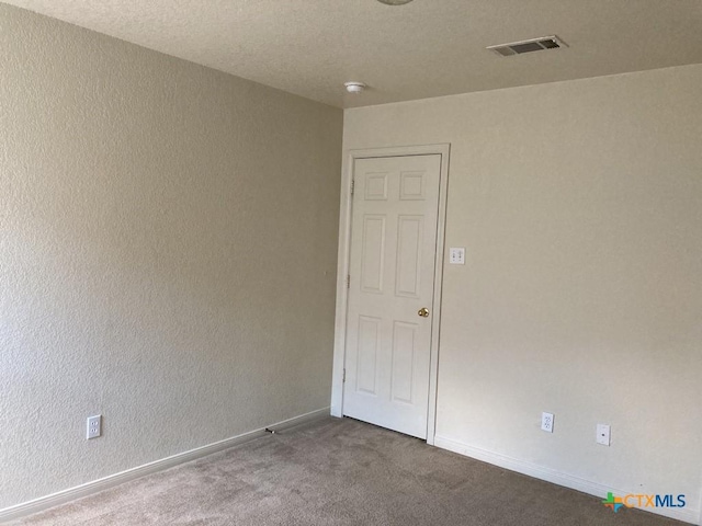 carpeted empty room with a textured ceiling