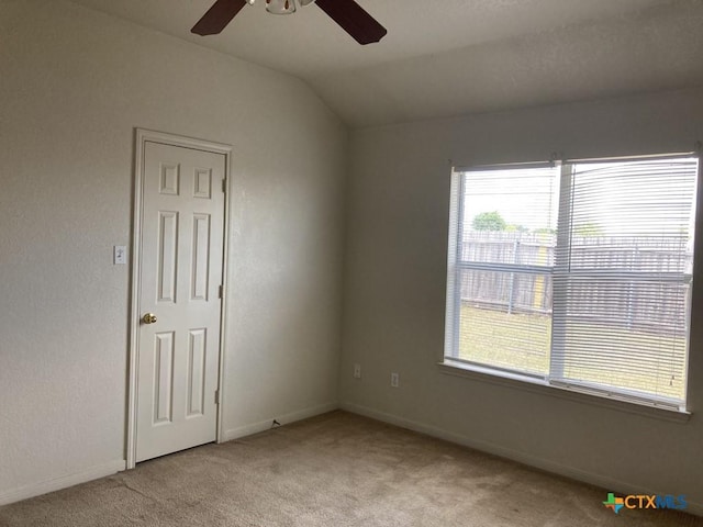 spare room with ceiling fan, lofted ceiling, and light carpet