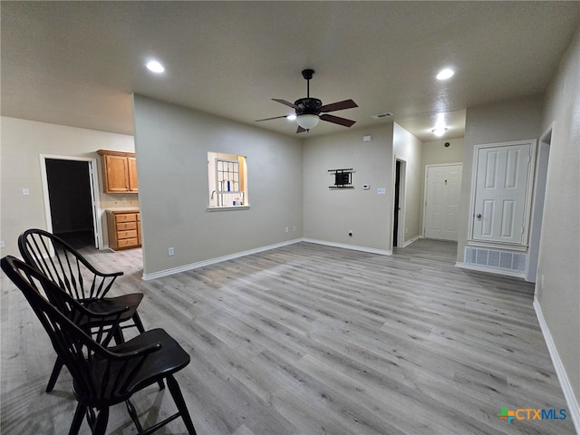 living area with a textured ceiling, light hardwood / wood-style floors, and ceiling fan