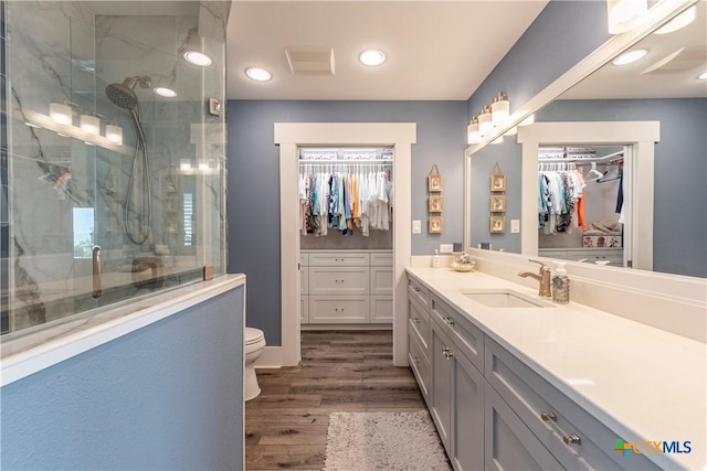 77 Sailfish Lndg, Port Lavaca, TX 77979 - full bathroom featuring vanity, wood finished floors, a walk in closet, a marble finish shower, and recessed lighting