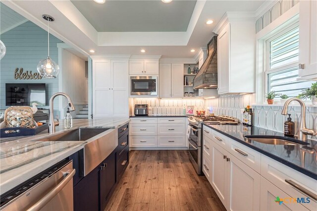 77 Sailfish Lndg, Port Lavaca, TX 77979 - kitchen featuring stainless steel appliances, custom range hood, white cabinetry, a raised ceiling, and dark stone counters
