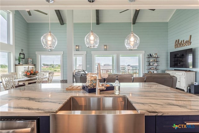 77 Sailfish Lndg, Port Lavaca, TX 77979 - kitchen with wood walls, healthy amount of natural light, light stone countertops, beamed ceiling, and an island with sink