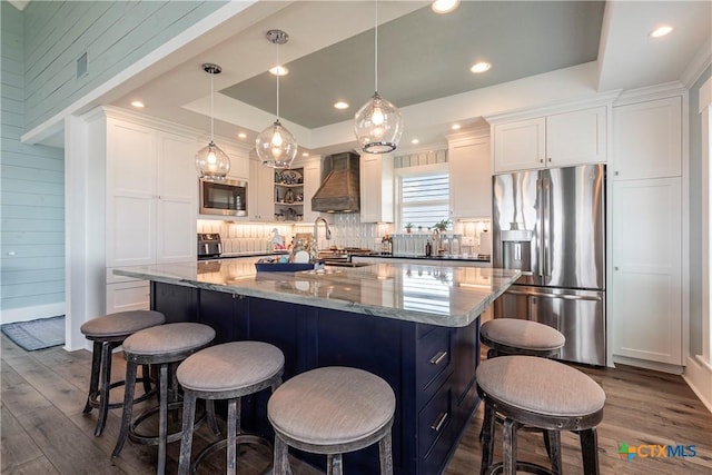 77 Sailfish Lndg, Port Lavaca, TX 77979 - kitchen with appliances with stainless steel finishes, a tray ceiling, custom range hood, white cabinets, and recessed lighting