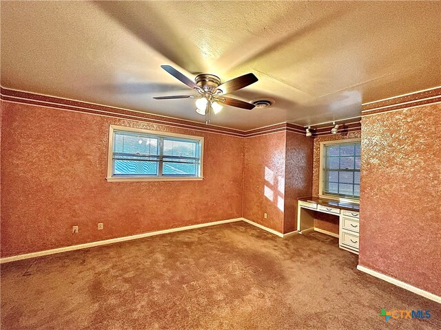 unfurnished bedroom featuring built in desk, ceiling fan, a textured ceiling, and ornamental molding