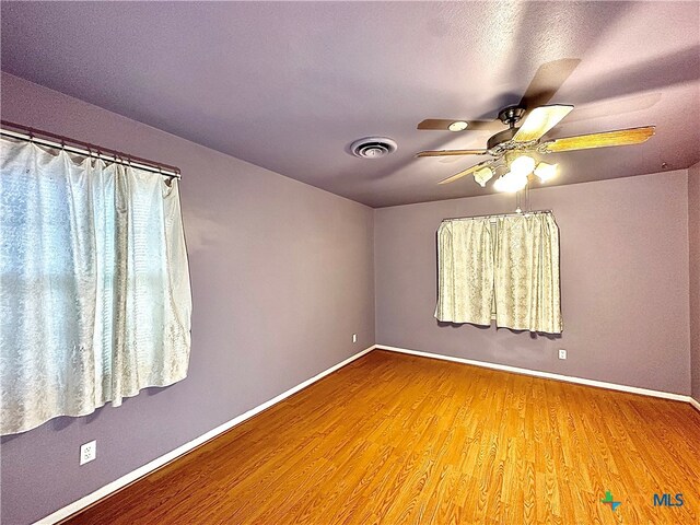 empty room with hardwood / wood-style floors and ceiling fan