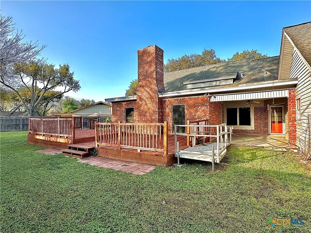 back of property with a wooden deck and a yard