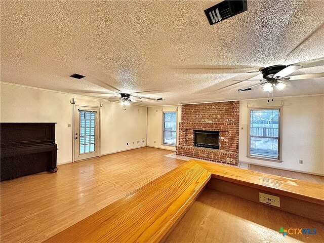 unfurnished living room with a fireplace, a wealth of natural light, hardwood / wood-style floors, and a textured ceiling