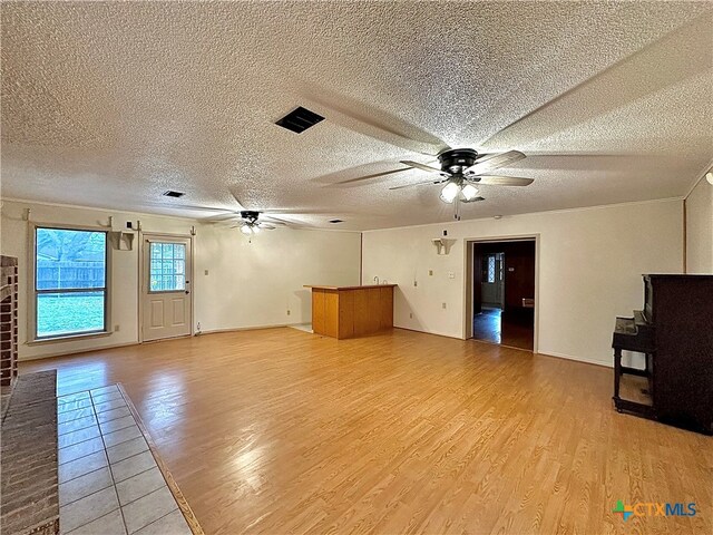 unfurnished living room featuring ceiling fan, a textured ceiling, and light hardwood / wood-style flooring