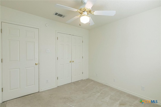 unfurnished bedroom featuring carpet floors, a closet, visible vents, a ceiling fan, and baseboards