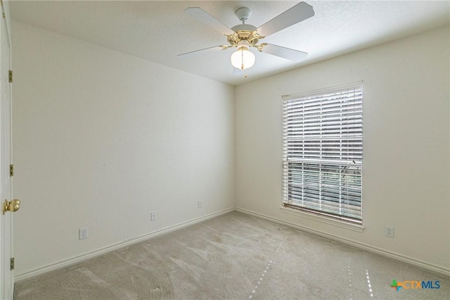 carpeted empty room with a ceiling fan and baseboards