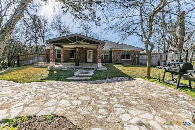 view of front of home with a patio area, brick siding, ceiling fan, and a fenced backyard