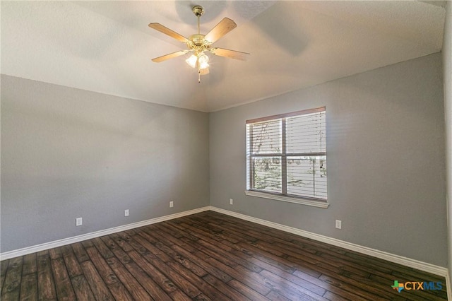 empty room with dark wood finished floors, a ceiling fan, and baseboards