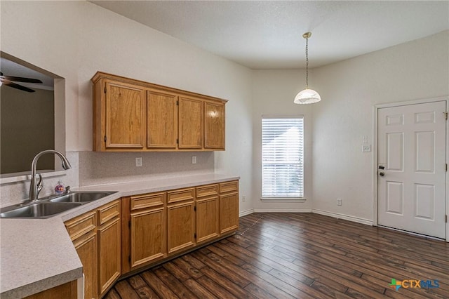 kitchen featuring brown cabinetry, dark wood finished floors, a sink, and light countertops