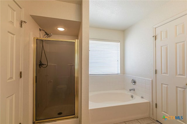 bathroom featuring a garden tub, a textured ceiling, tile patterned flooring, and a shower stall