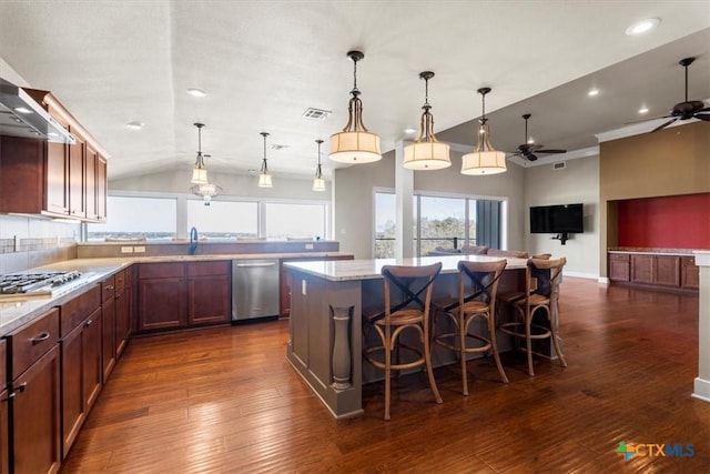 kitchen with a breakfast bar, decorative light fixtures, a center island, appliances with stainless steel finishes, and light stone countertops