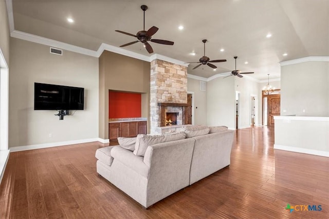 living room featuring high vaulted ceiling, ornamental molding, hardwood / wood-style floors, a fireplace, and ceiling fan with notable chandelier