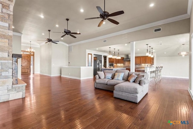 living room with crown molding, dark wood-type flooring, and ceiling fan with notable chandelier