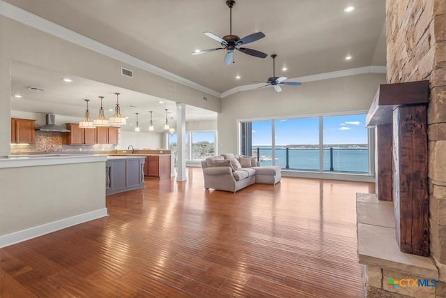 unfurnished living room with lofted ceiling, crown molding, ceiling fan, a water view, and wood-type flooring