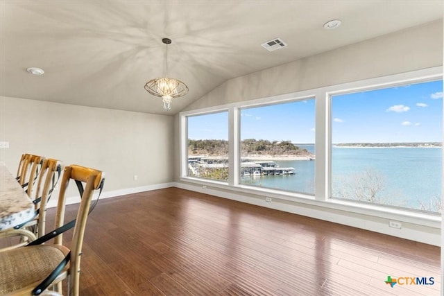 unfurnished dining area with wood-type flooring, vaulted ceiling, a chandelier, and a water view