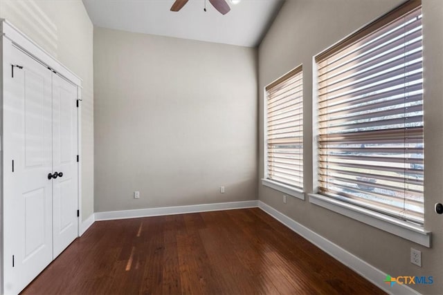 unfurnished bedroom with lofted ceiling, dark hardwood / wood-style floors, ceiling fan, and a closet