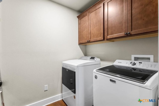 washroom with washer and dryer and cabinets