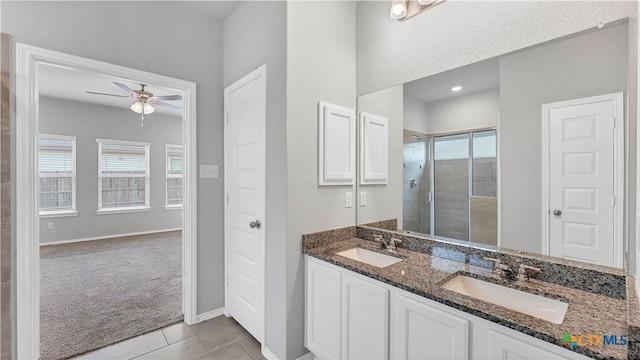 full bath with ceiling fan, a stall shower, tile patterned flooring, and a sink