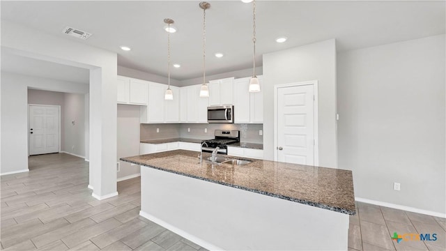 kitchen featuring dark stone counters, appliances with stainless steel finishes, a sink, and tasteful backsplash