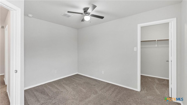 unfurnished bedroom with carpet floors, visible vents, baseboards, a closet, and a walk in closet