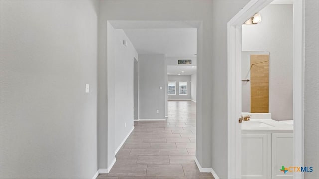 corridor featuring baseboards and a sink