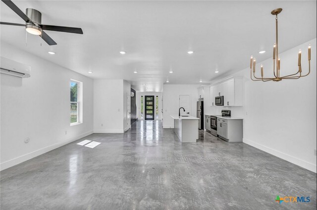 unfurnished living room featuring ceiling fan with notable chandelier, sink, a wealth of natural light, and concrete floors