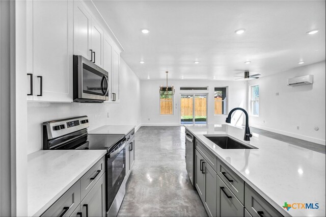 kitchen featuring concrete flooring, stainless steel appliances, ceiling fan, sink, and pendant lighting