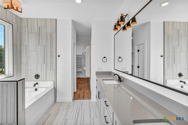 bathroom with a bath, vanity, a healthy amount of sunlight, and wood-type flooring