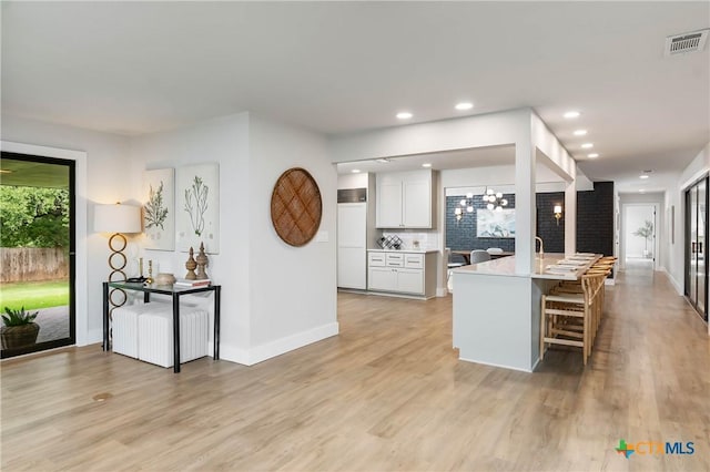 9 Mission Trce, New Braunfels, TX 78130 - kitchen featuring a kitchen breakfast bar, white cabinetry, light countertops, light wood finished floors, and decorative backsplash