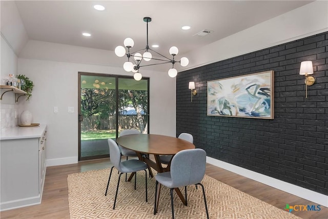 9 Mission Trce, New Braunfels, TX 78130 - dining room featuring an accent wall, light wood-style floors, a chandelier, recessed lighting, and brick wall