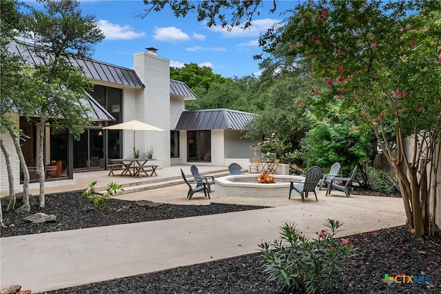 9 Mission Trce, New Braunfels, TX 78130 - back of house featuring a standing seam roof, a fire pit, a chimney, a metal roof, and a patio area